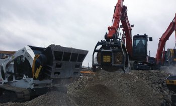 Drticí lopata na smykovém nakladači a otevřená bubnová třídicí lžíce na malém rypadle