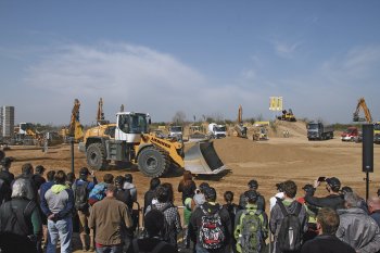 Davy lidí sledují, jak kolem nich projíždí kolový nakladač Liebherr L 580