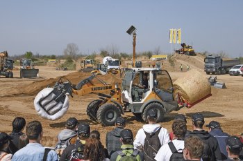 Přijíždí také kolový nakladač Liebherr L 506 Compact, který veze rovnou dva balíky slámy
