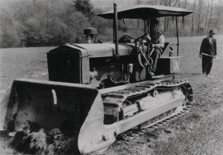 Traktor FAMO Rübezahl s buldozerovou radlicí v pohledu z levé strany. Podélné táhlo vedené v celé délce stroje sloužilo k přenosu síly od hydraulického válce vzadu na zdvihací ústrojí radlice. Převzato z www.bauforum24.biz.