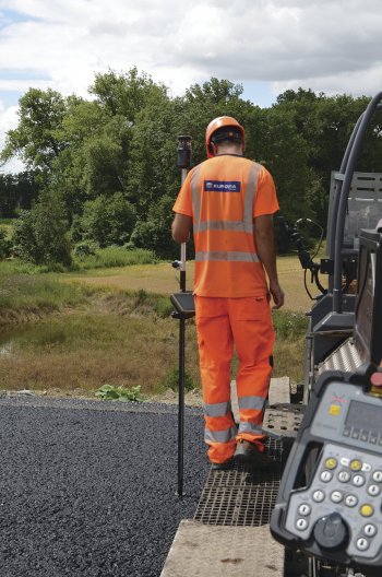 Zaměstnanec společnosti EUROVIA CS kontroluje absolutní výšku za pohybujícím se finišerem.