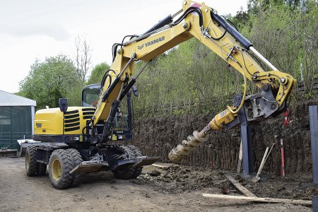 Yanmar B110W firmy Repont s nasazeným vrtákem při stavbě opěrné zdi.