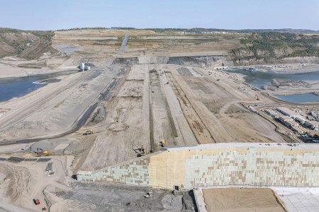 Rýpadla, dozery a válce v akci při výstavbě rozsáhlé přehradní nádrže se sypanou hrází a vodní elektrárnou na řece Peace v Kanadě.
