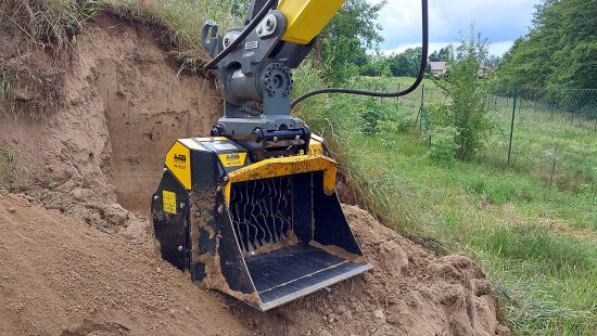 Pásové minirýpadlo je vybavené hydraulickým rychloupínačem, naklápěcí hlavou Powertilt a třídicí rotorovou lžící MB Crusher MB-HDS307.