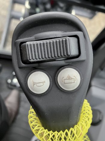 Detail pravého joysticku. Tlačítkem vpravo aktivuje strojník přídavný hydraulický okruh pro powertilt.