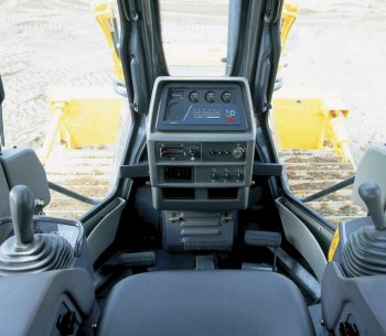 Interiér kabily Komatsu D65-12. Levý joystick slouží pro pojezd, pravý pro ovládání radlice.